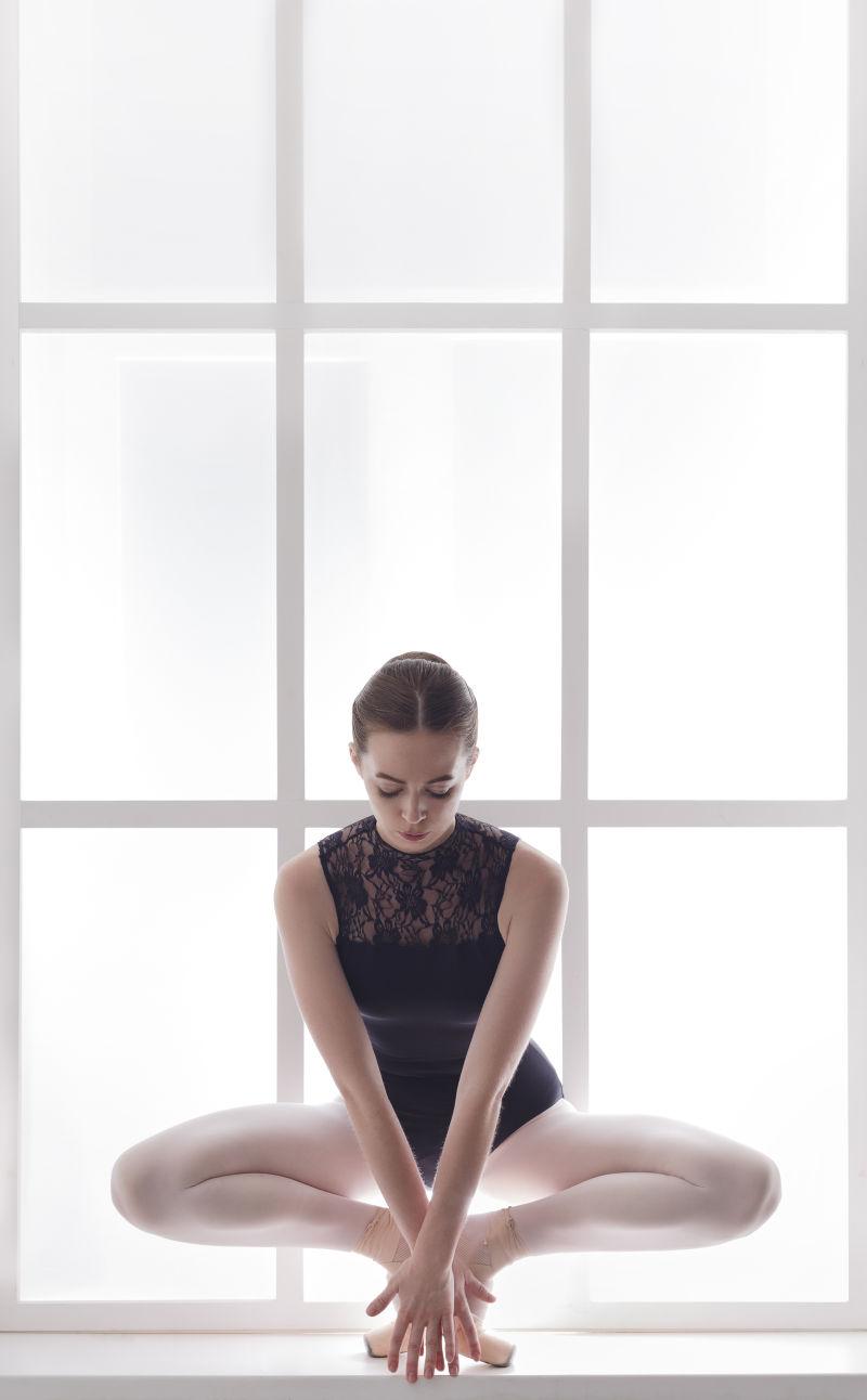 白色窗台上练习芭蕾舞姿的外国女孩