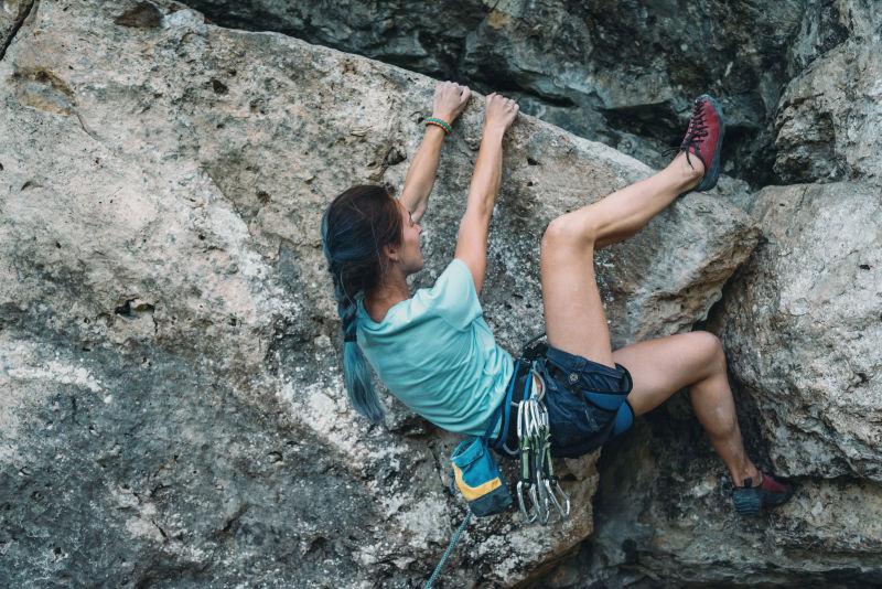 穿着安全装备的年轻女子在山上攀岩