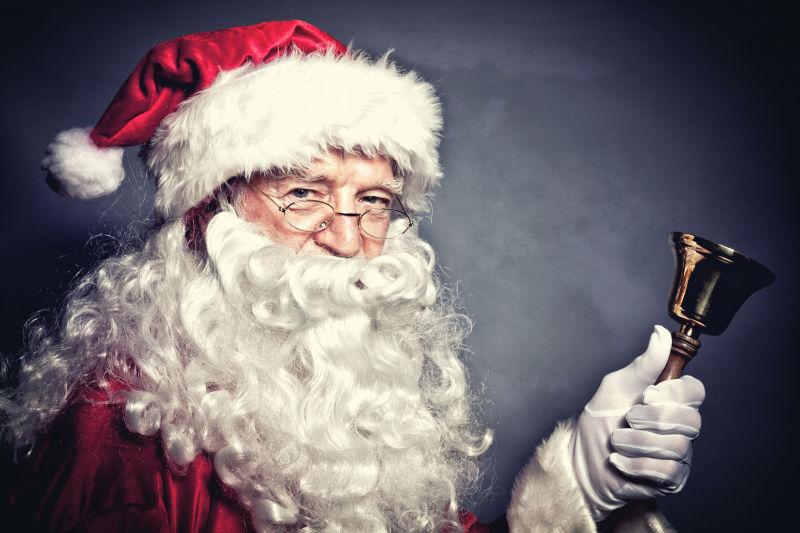 灰色背景下的圣诞老人手里的铃铛