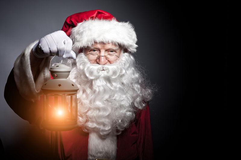 灰色背景下的圣诞老人手里的夜游灯