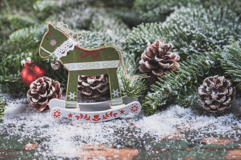 雪中的圣诞树上的松果和一个迷你小木马