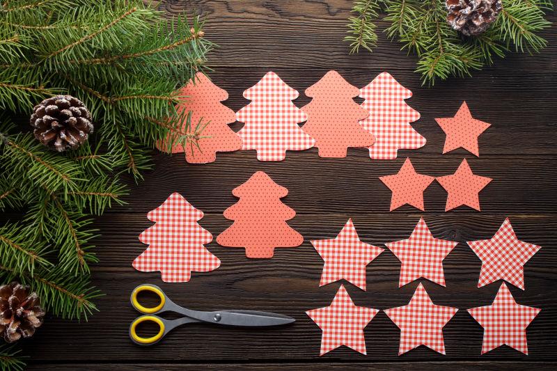 木质桌板上用剪子剪成的圣诞树卡片和五角星