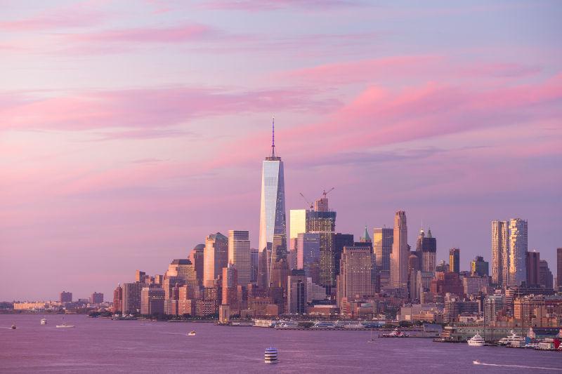 有晚霞的天空下黄昏的纽约市曼哈顿市建筑天际线