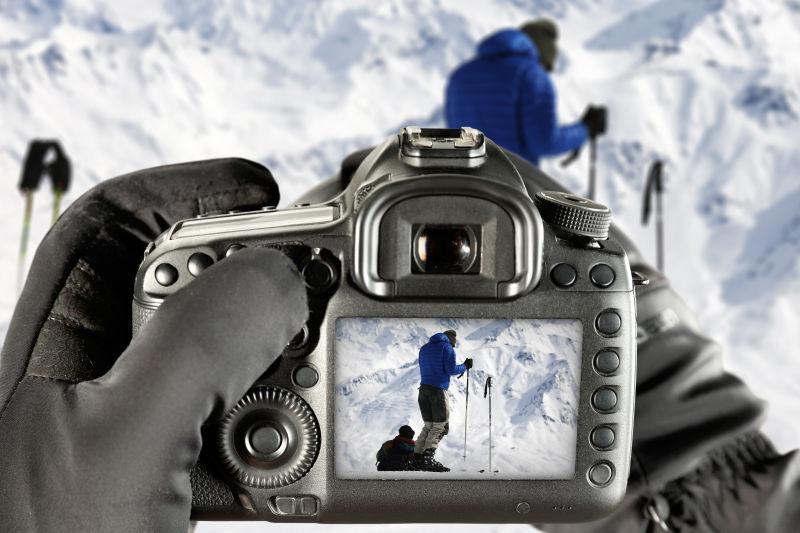 雪地上拿着相机拍照的滑雪人