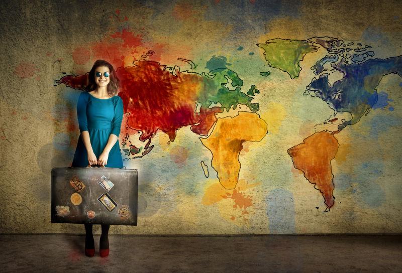 世界地图背景前提着行李箱的女孩