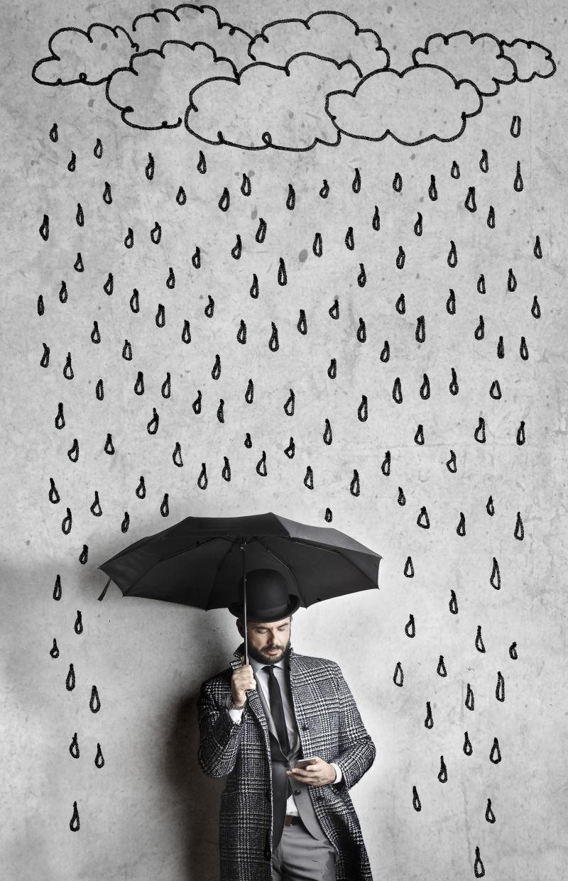 下雨背景中打伞看手机的男人