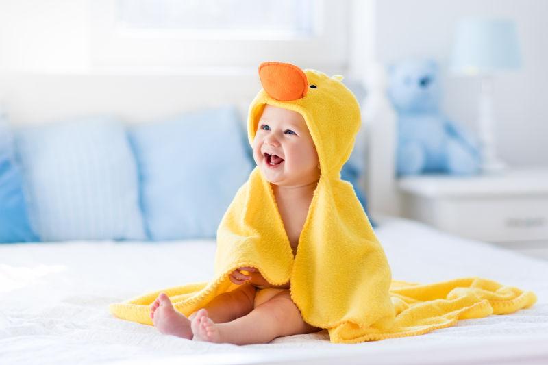 穿着黄色鸭子浴巾的快乐婴儿