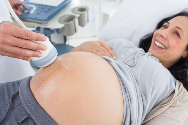 微笑的孕妇在医院接受超声波检查