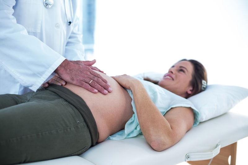 躺在医院的床上接受医生检查的微笑的孕妇