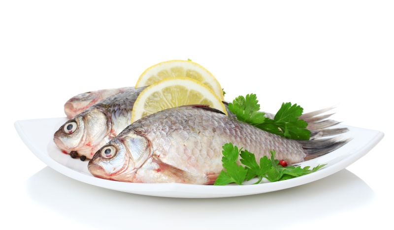 白色盘子中的三条鱼与食材配料