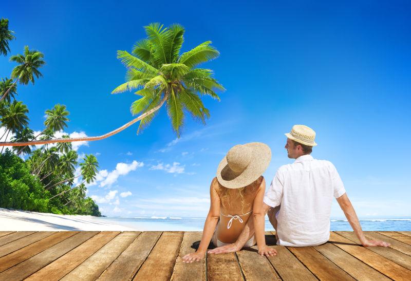 在热带坐在木板上度假的年轻夫妇