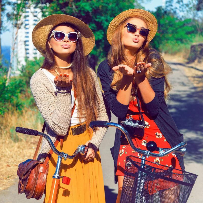 小路上的两个美女朋友带着帽子汽车自行车