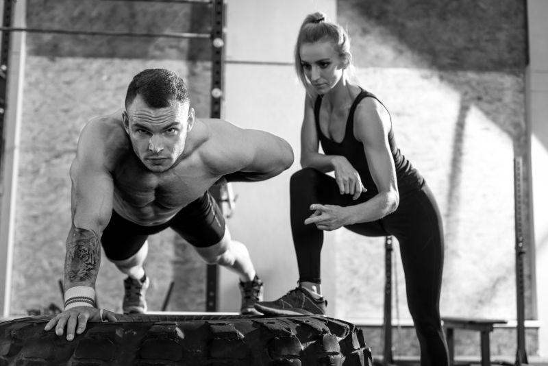 漂亮女人看着男人在健身房锻炼时数着俯卧撑的量
