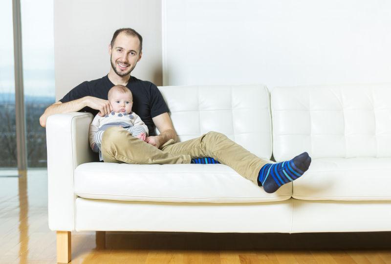 坐在沙发上的父亲与婴儿