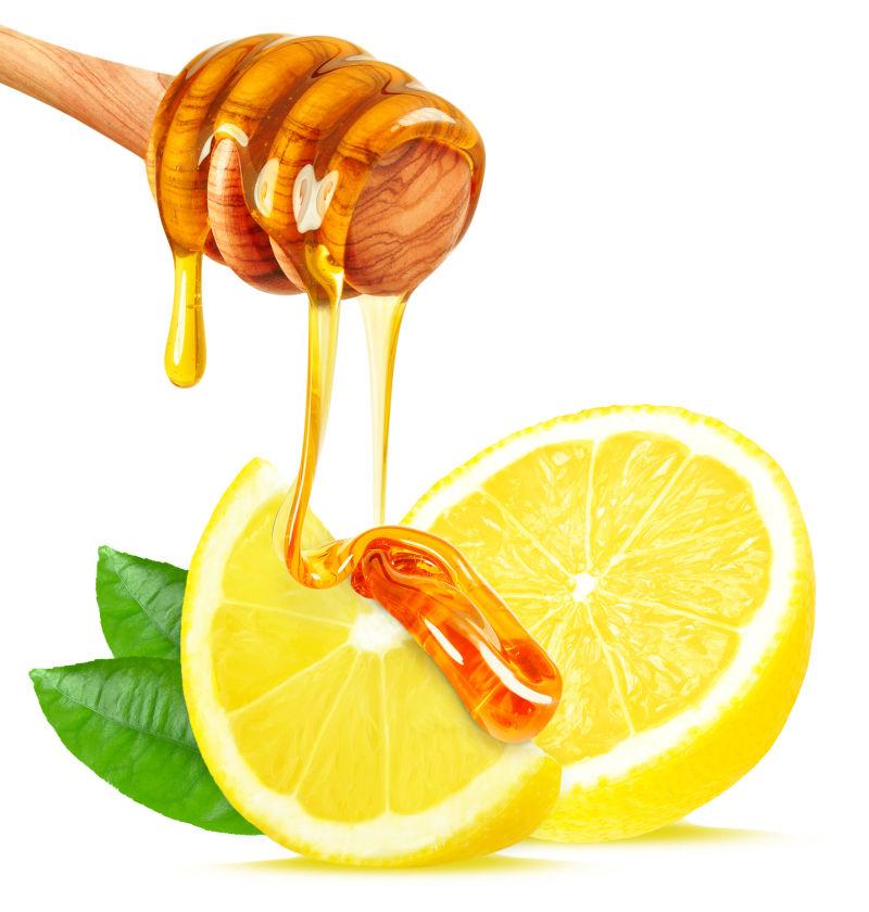 白色背景下滴在柠檬上的美味的蜂蜜