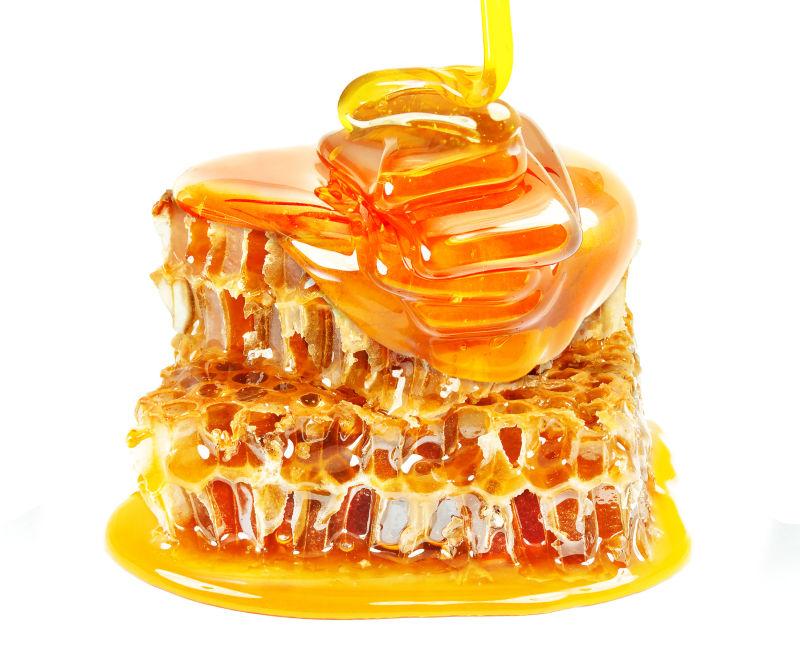 白色背景下金黄色透明的蜂蜜和蜂巢