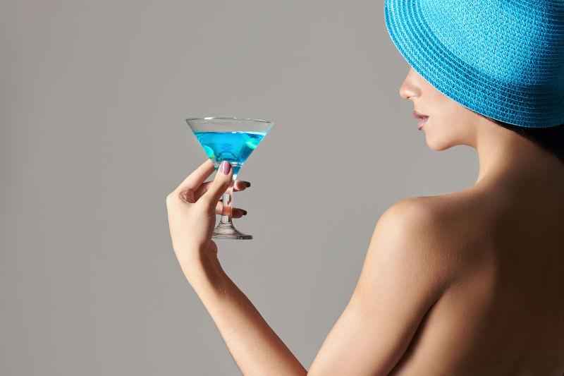 端着蓝色鸡尾酒带着蓝色帽子的美女