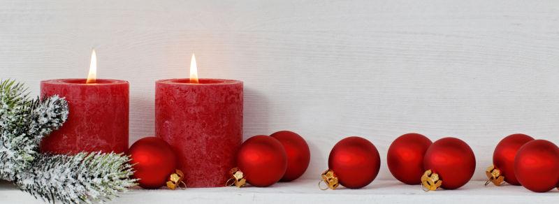 两支燃烧的圣诞节红色蜡烛与装饰品