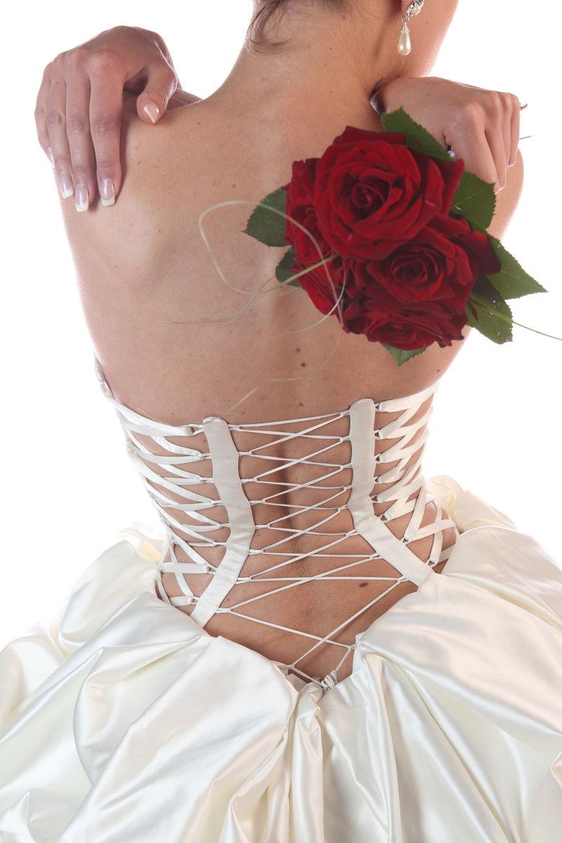 白色背景下拿着手捧花的新娘的背影