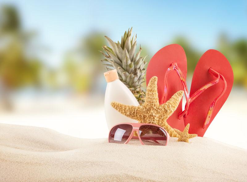 夏日沙滩上的菠萝海星拖鞋和防晒乳