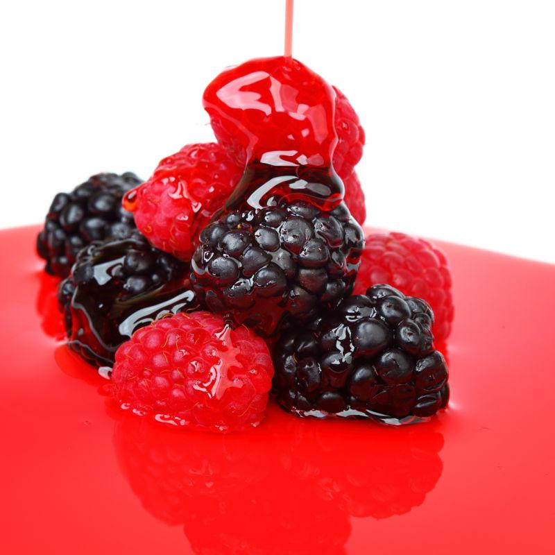 白色背景下红色果酱上红色和黑色浆果的甜点