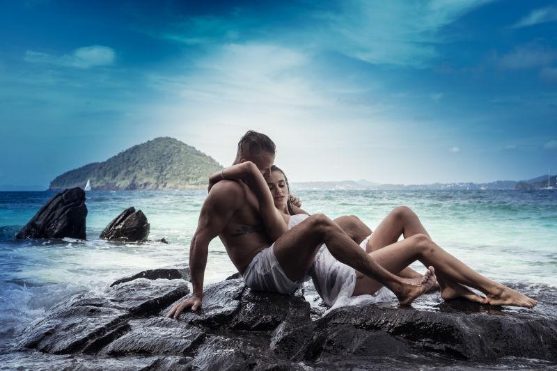 坐在海边的岩石上的一对情侣