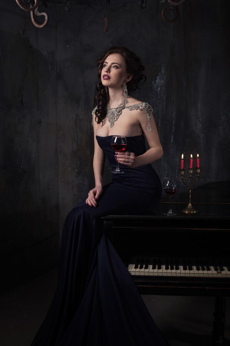 美女穿着黑色的裙子坐在钢琴上