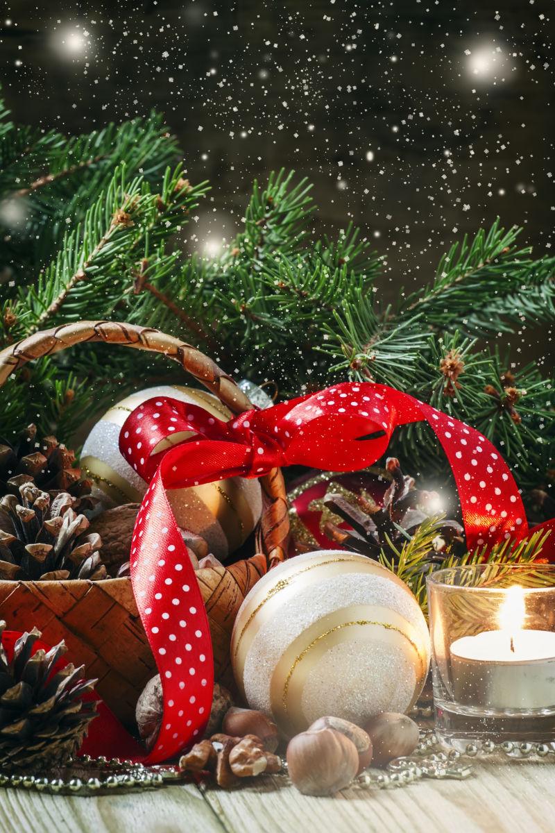 木桌上的圣诞树枝和各种圣诞饰品还有点燃的蜡烛