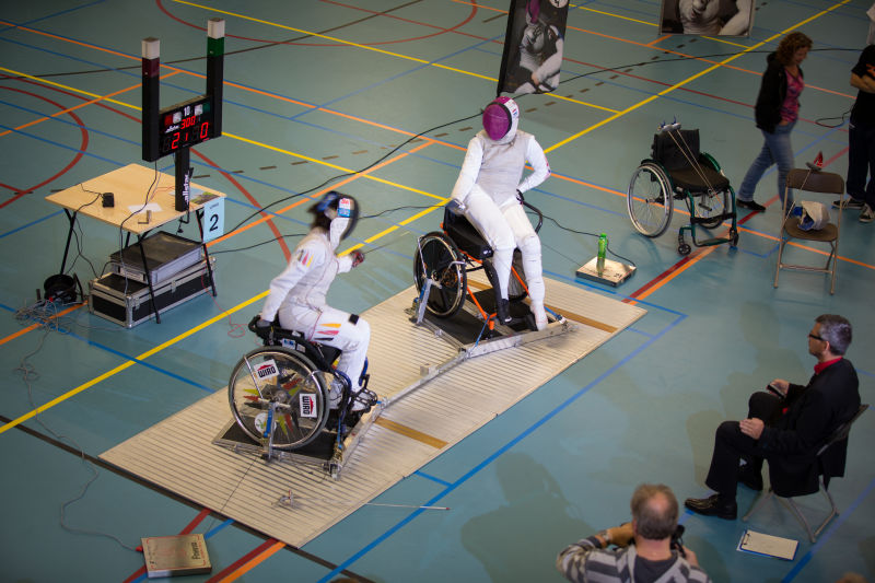 两位残疾运动员坐在轮椅上击剑