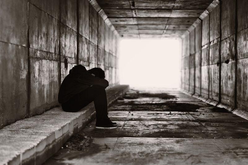一个孤独的男孩坐在隧道右侧的路边