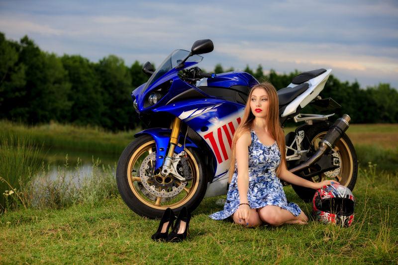 河边草地摩托车旁的美丽年轻女子
