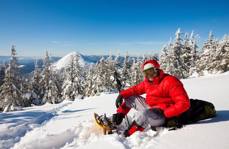 冬天坐在雪地上的徒步旅行者