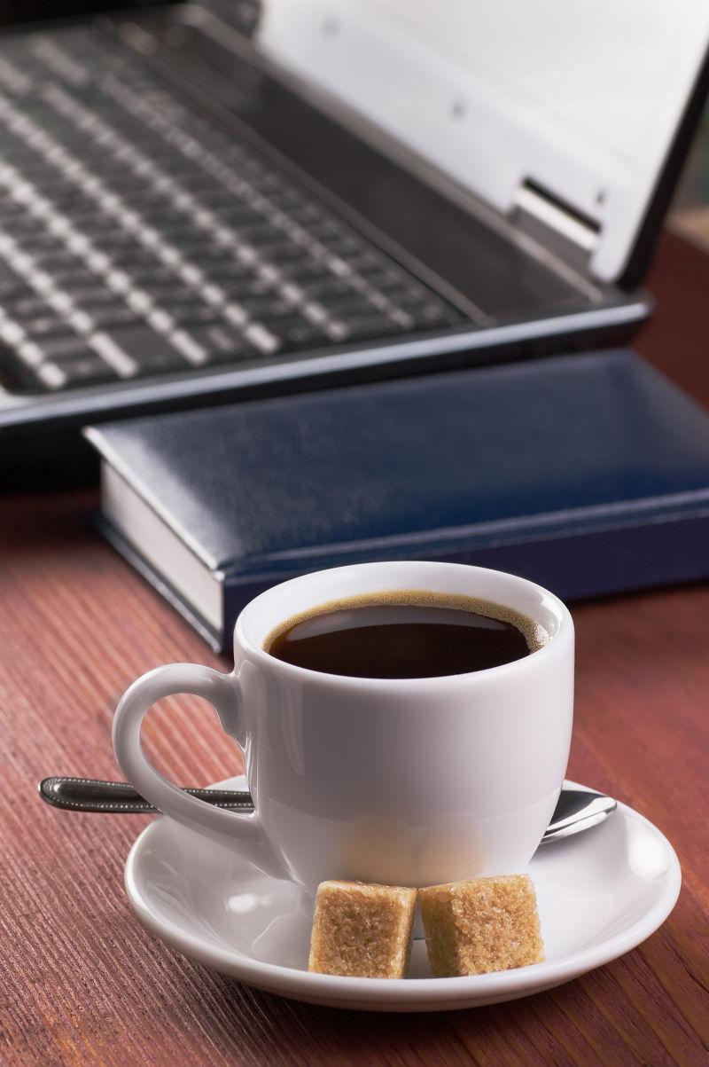 木桌上笔记本电脑旁边的一杯咖啡