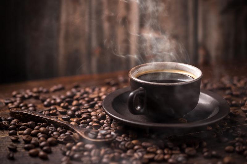 深色背景下的咖啡豆上的一杯热咖啡