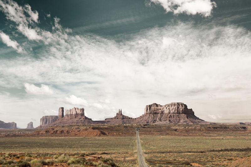 有云的天空下通往纪念碑谷的沙漠公路全景