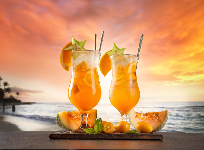 夕阳海边背景下的两杯水果饮料