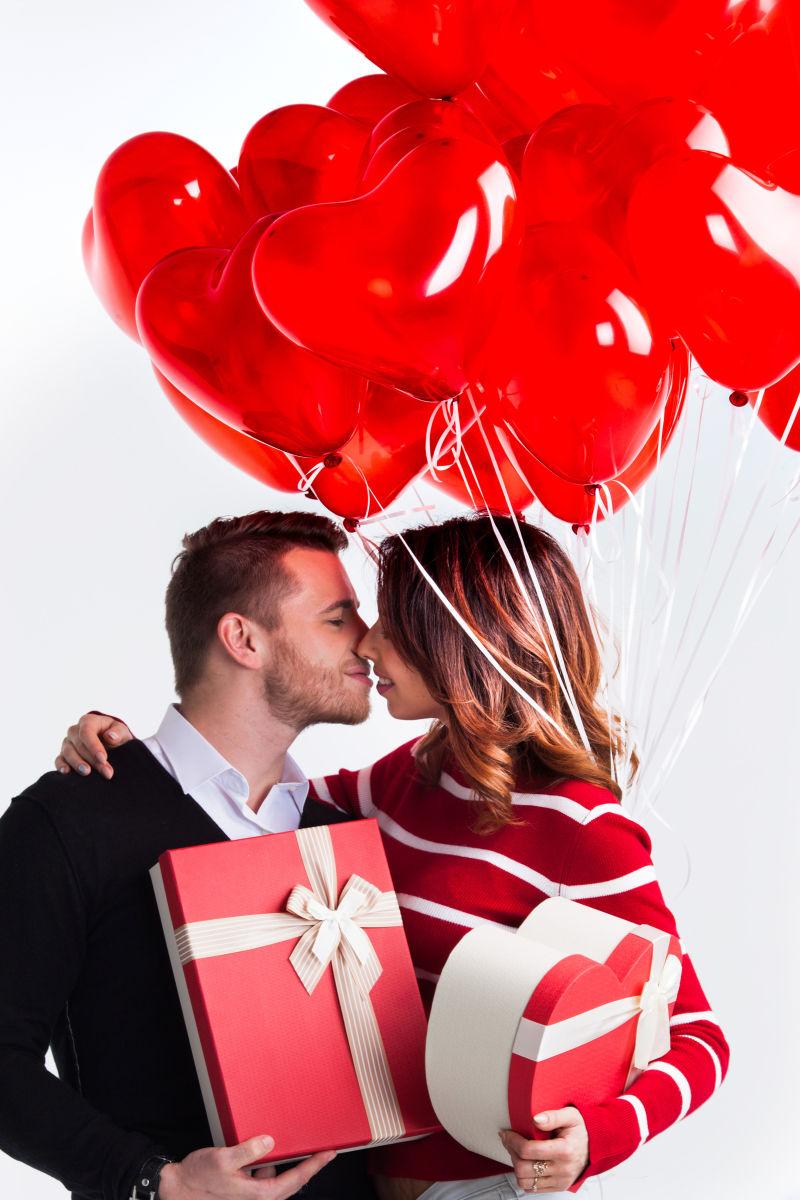 一对拿着情人节礼物和红气球的情侣