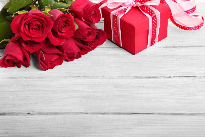 木板上的玫瑰花束和红色礼物盒