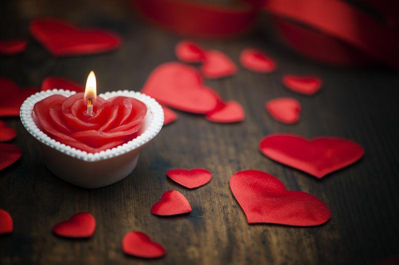 木板上的红心纸片和玫瑰形状的蜡烛