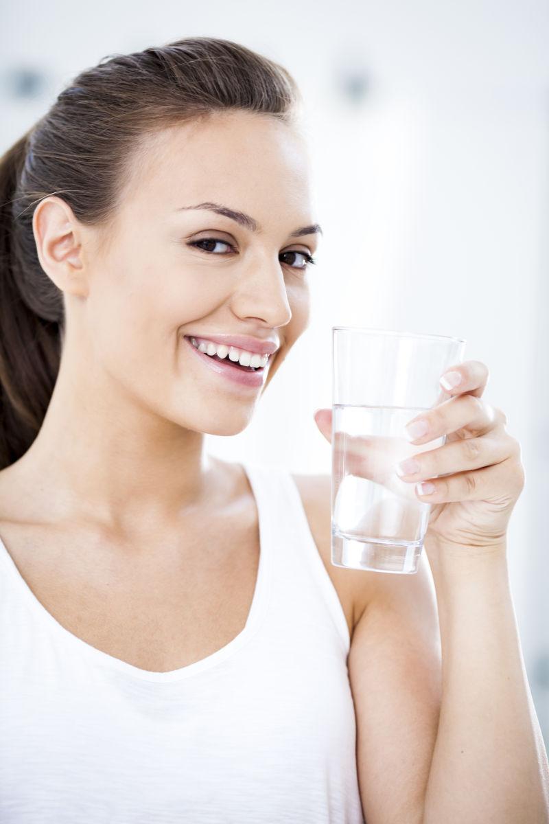 微笑的年轻女子拿着一杯水