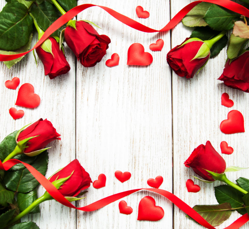 木桌上美丽的红玫瑰和红色丝带还有爱心装饰品