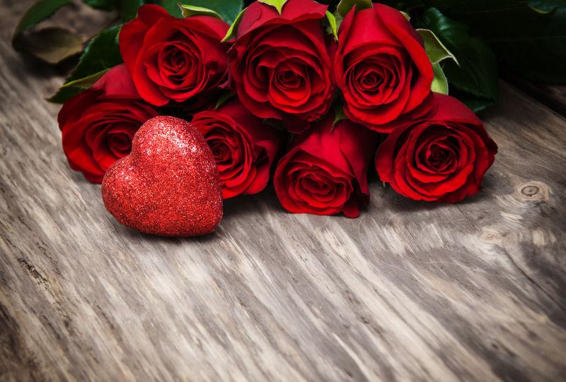 桌子上美丽的红玫瑰花束和一个红色爱心