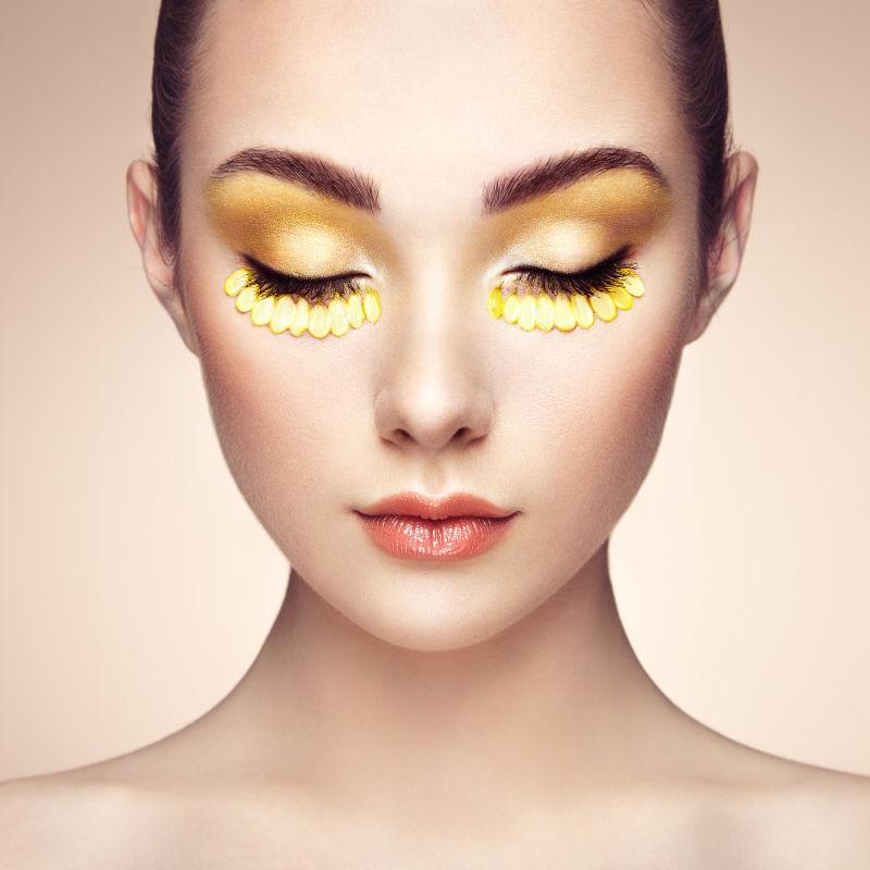 金色眼影用鲜花装饰的美丽女人的脸
