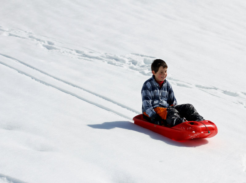 男孩坐在雪橇车里滑雪