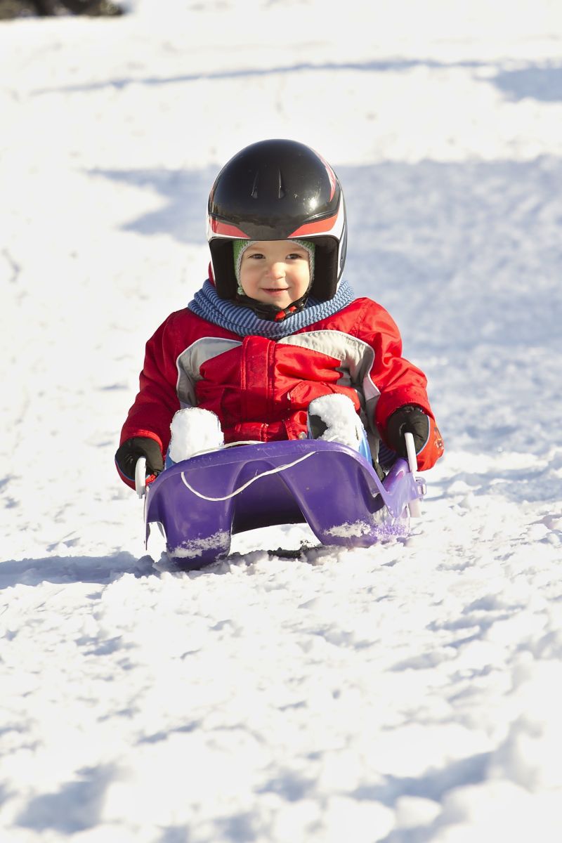 幼儿坐在雪橇车里滑雪