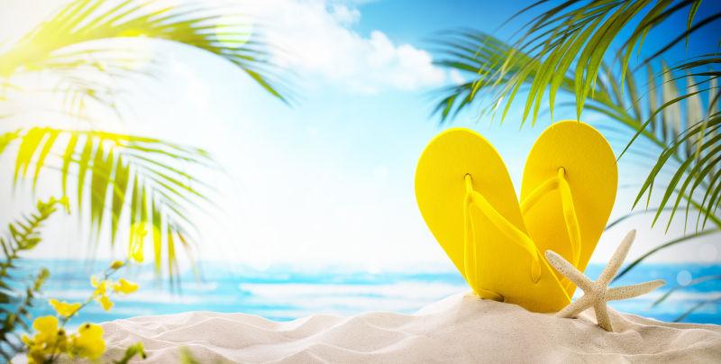 美丽的海滩上一双黄色人字拖与海星