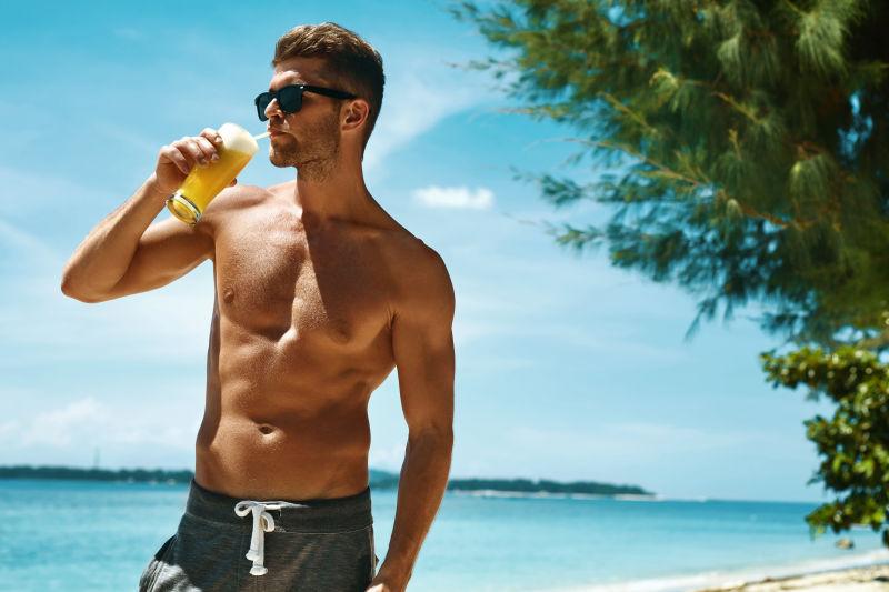 在沙滩上喝果汁的男人