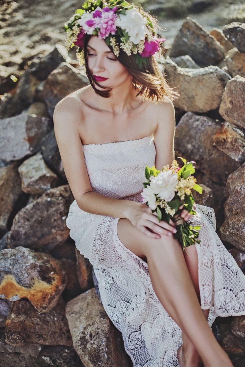 坐在石头上戴着花环拿着捧花的白衣裙美女