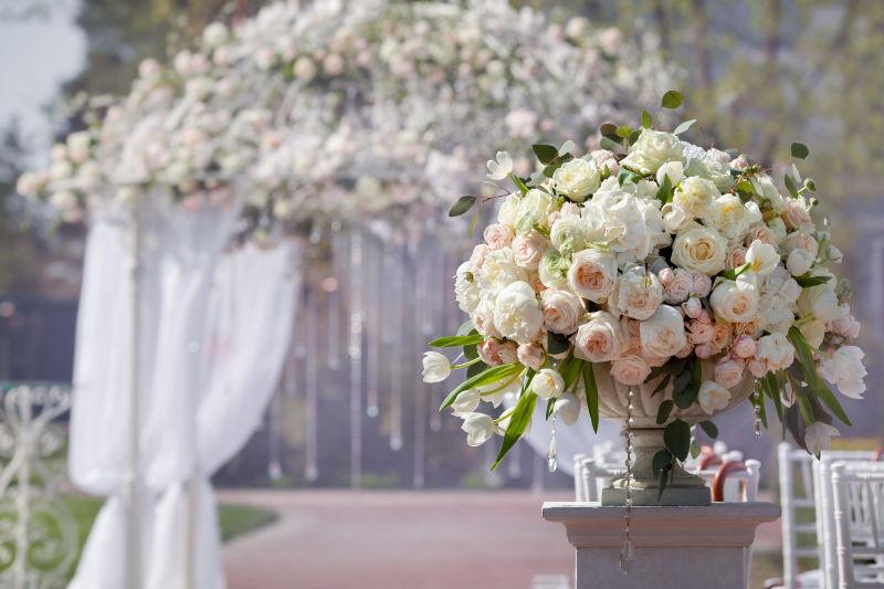 婚礼拱门背景上花瓶中美丽的玫瑰花束