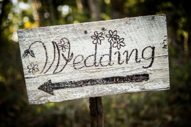 自制的乡村婚礼标志放在树林里的铲子上